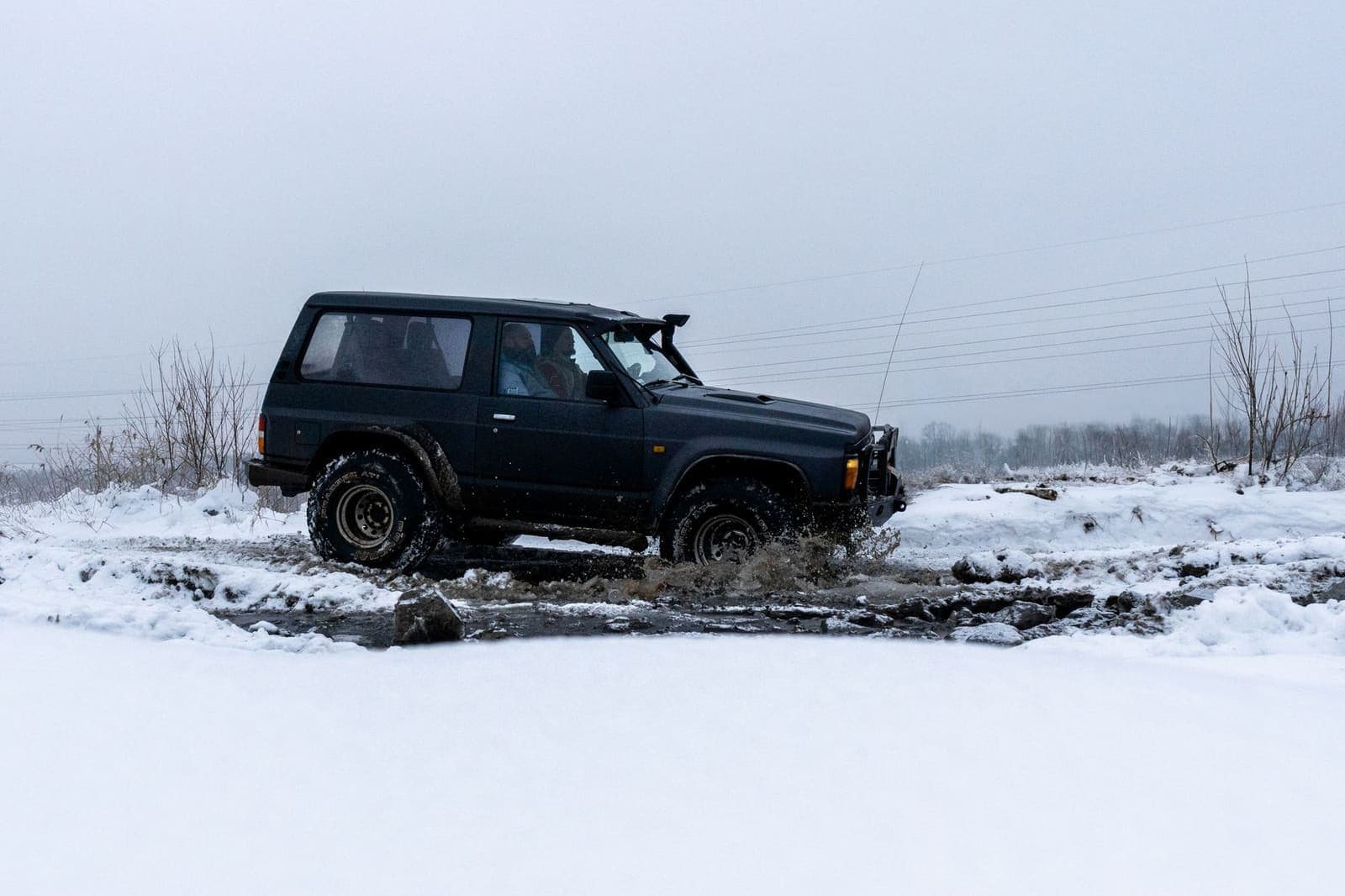 Terreinauto rijdt door de sneeuw over een besneeuwde weg