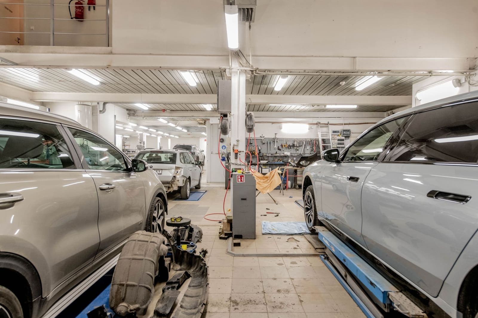 Autowerkplaats met meerdere auto's binnen en gereedschap langs de wand