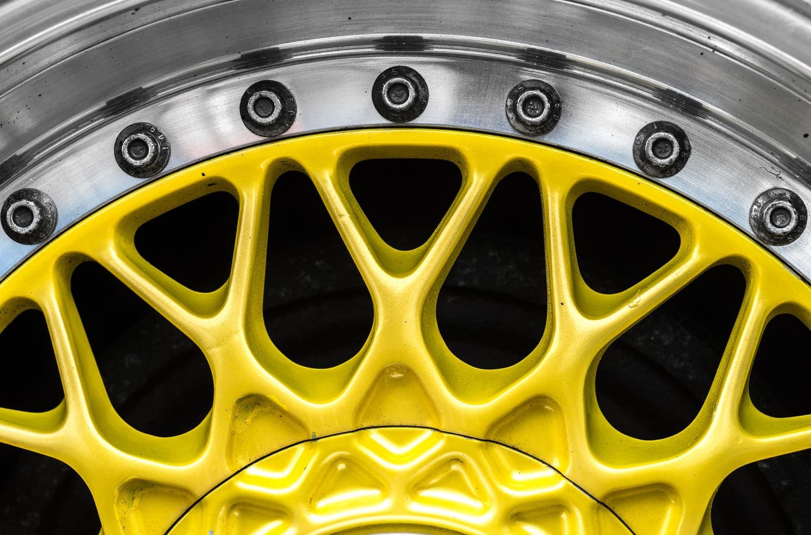 Lichtmetalen velg met geel middendeel en zichtbare velgbouten, van dichtbij